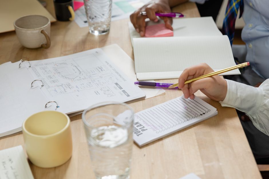 A diverse team engaged in a collaborative business meeting with notebooks and a planner.
