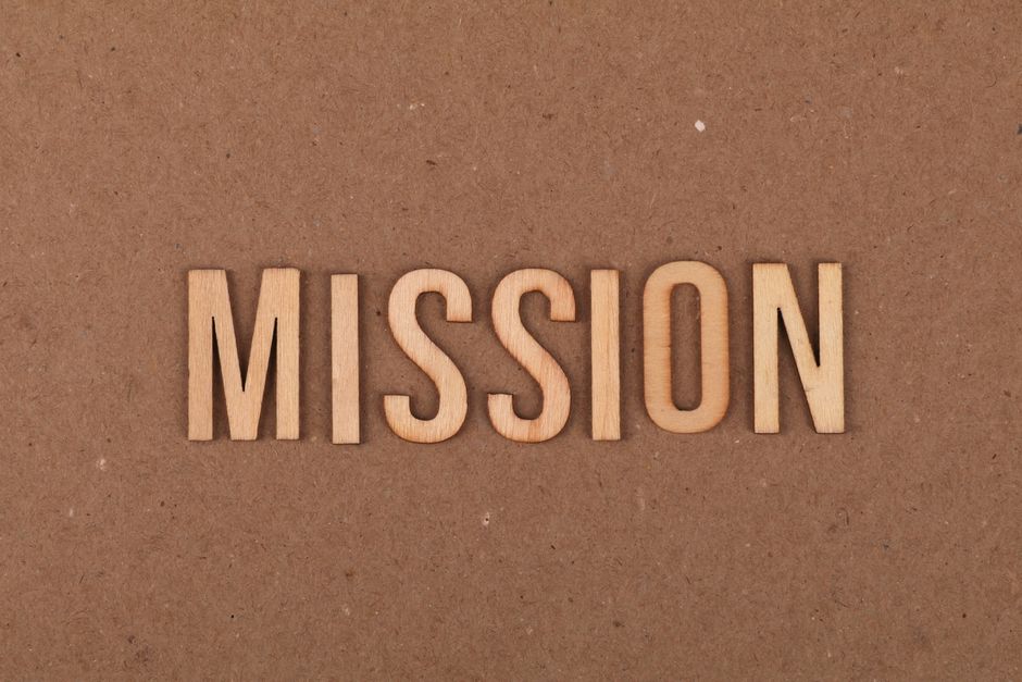 Wooden letters spelling 'MISSION' on textured cardboard background, emphasizing goals and purpose.